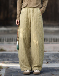 Woman wearing olive green quilted wide leg pants with brown top and beige sneakers