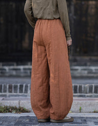 Back view of women's relaxed balloon orange harem pants in textured linen fabric