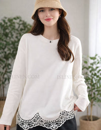 Woman wearing a white blouse with lace details and a straw hat indoors.